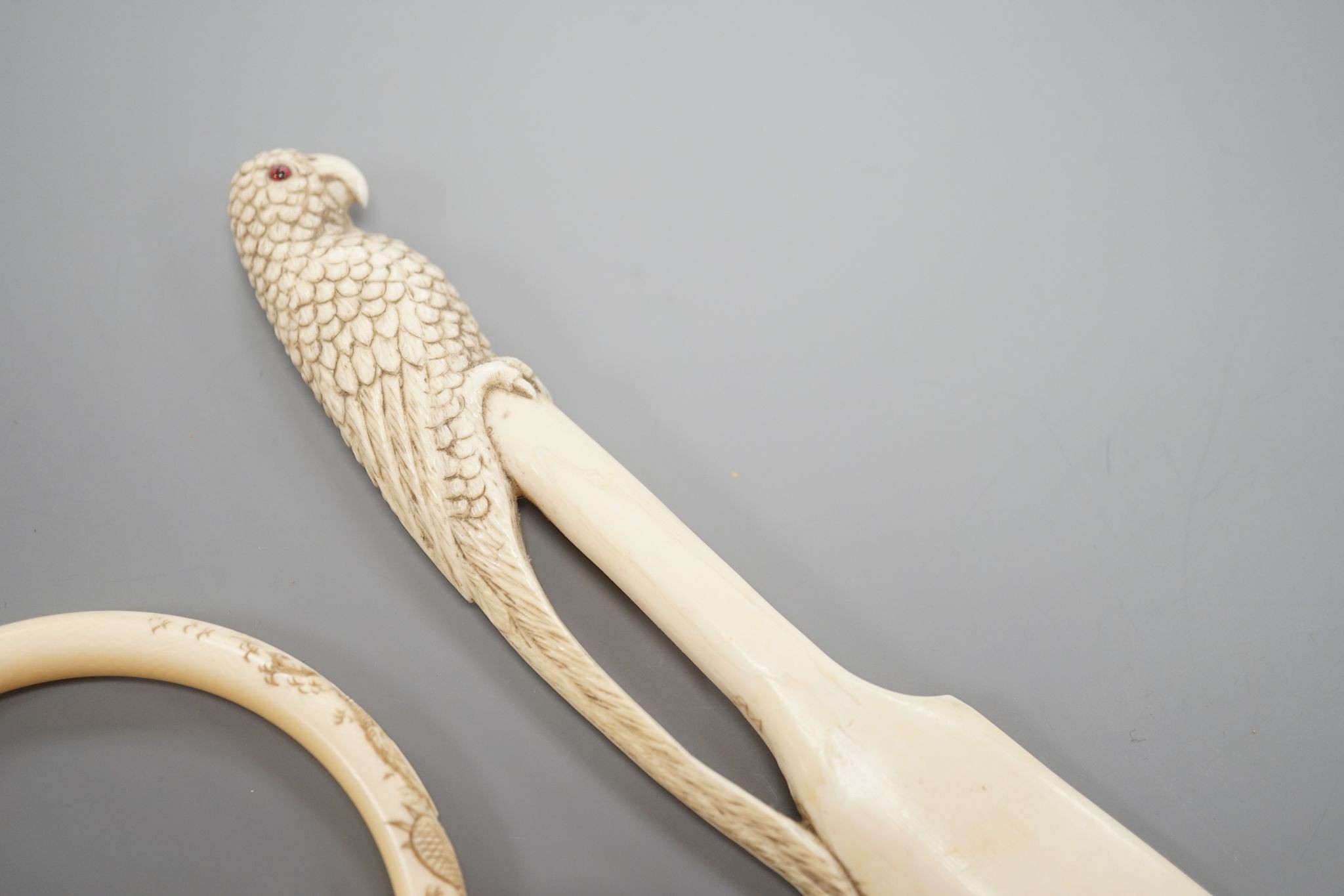 A late 19th century carved ivory ‘parrot’ paper knife and two Japanese carved Ivory bangles, paper knife 22 cms long.